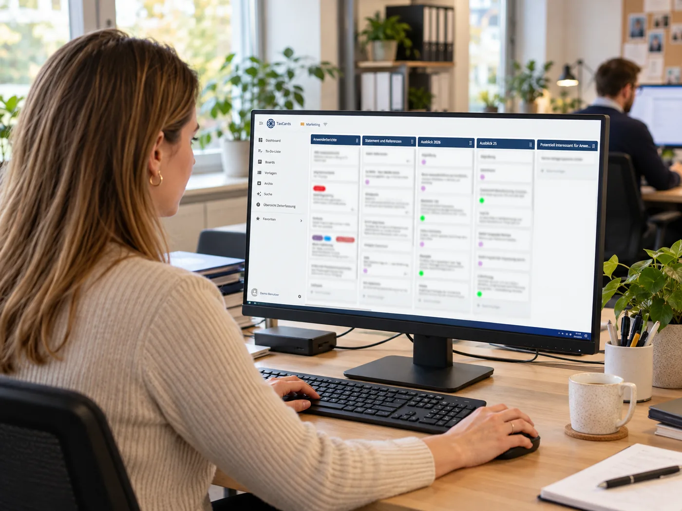 Mitarbeiterin im Büro arbeitet am Bildschirm mit einem TaxCards-Board