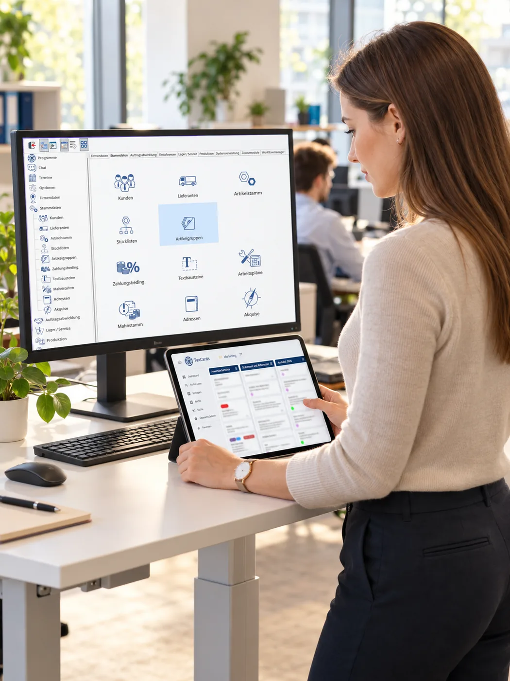Mitarbeiterin arbeitet am Bildschirm mit TaxMetall und parallel auf dem Tablet mit einem TaxCards-Board